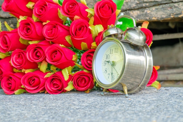 Photo alarm clock by artificial roses on retaining wall