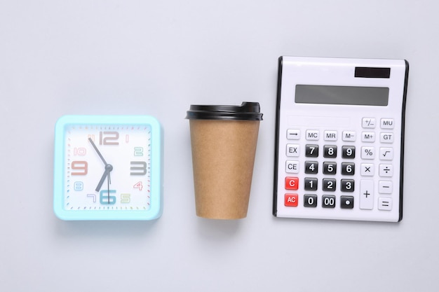 Alarm clock calculator and craft coffee cup on gray background