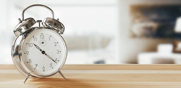 Alarm clock closeup have a good day with a cup of coffee and flower pots background in the morning sunlight.