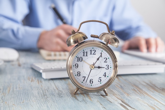 Alarm clock on the desk. Businessman working in office