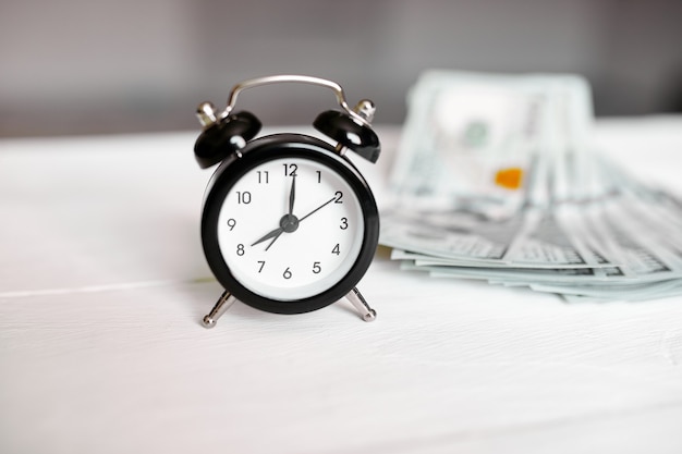 Alarm clock and money on white wooden background, Time is money concept