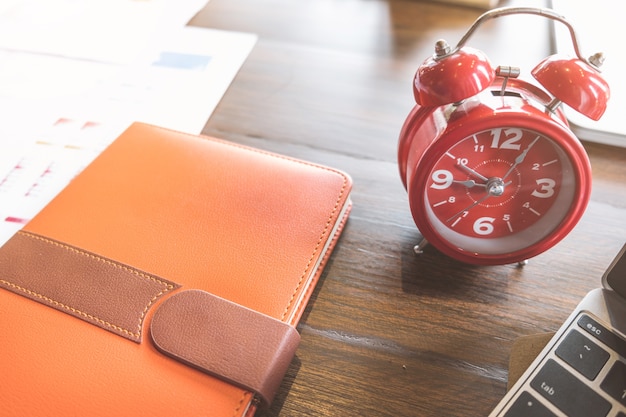 Alarm clock,notebooke and computer laptop on wooden table in office