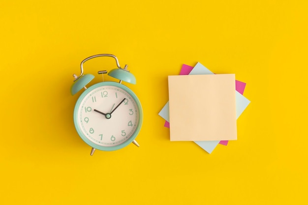 Photo alarm clock and paper speech bubble with space for text on yellow background