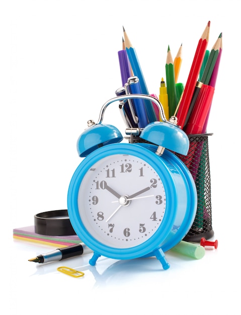 Alarm clock and school supplies  on white