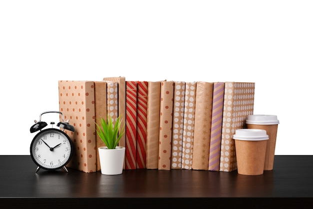 Alarm clock stack of books and cup on tabletop against white background