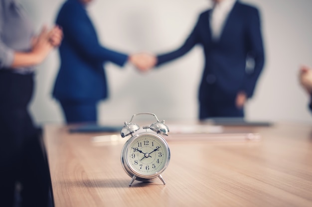 Photo alarm clock on  table with business people  in seminar room.