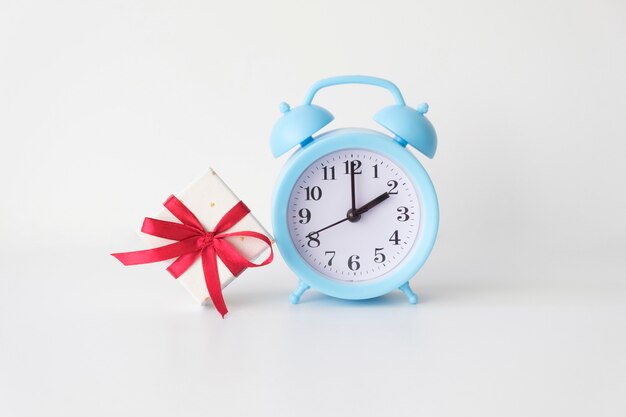 Alarm clock with gift on the white background.