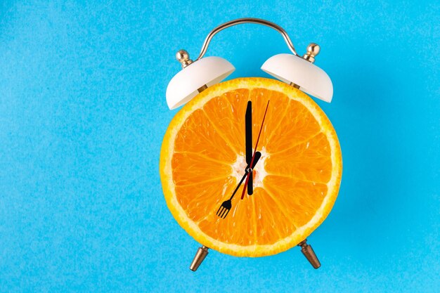 Alarm clock with an orange instead of a dial on a blue background, place for text