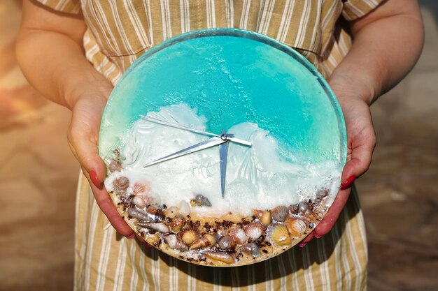 An alarm clock with seashells sea wave and send in woman hand vacation time Beach Time