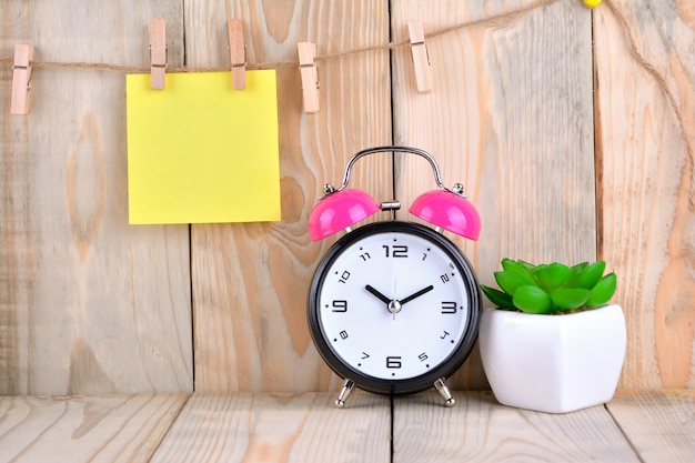 Alarm clock with sticky note on wooden table