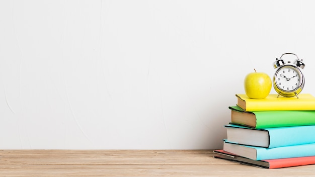 Alarm clock and yellow apple on stack of books