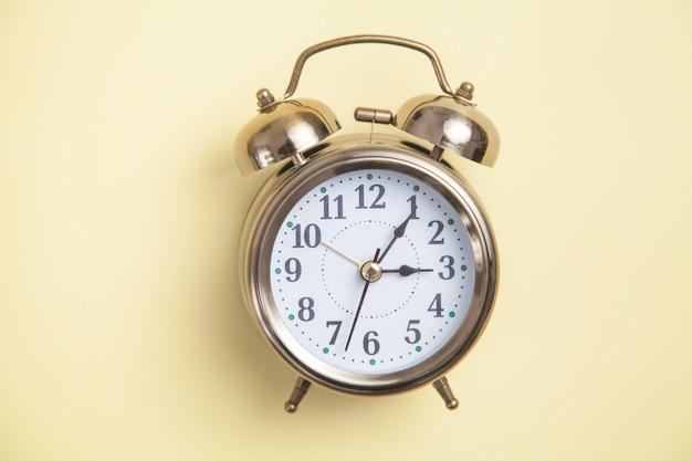 Alarm clock on yellow background. Top view