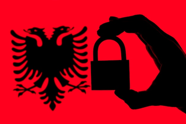 Photo albania security silhouette of hand holding a padlock over national flag