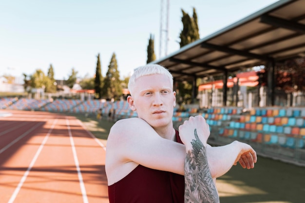 Albino male athlete running track stretching, champion