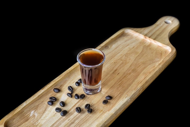 Alcohol shot made of coffee on wooden board with coffee beans with copy space