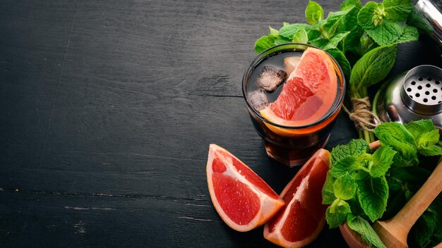 Alcoholic cocktail of brandy mint grapefruit Whiskey On a black wooden background Free space for text