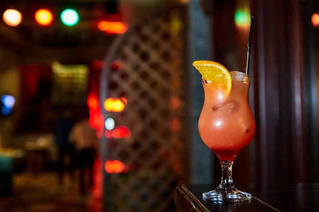 Alcoholic cocktail decorated with half slice of orange on the bar counter of a nightclub