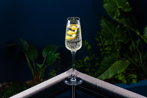 Alcoholic cocktail on a transparent table against a blue background and plants