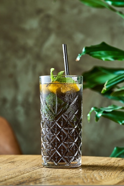 Alcoholic cocktail with gin and cola, lime and mint in a glass with ice