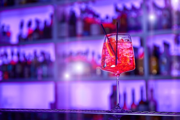 Alcoholic cocktail with ice and a piece of orange on the bar counter