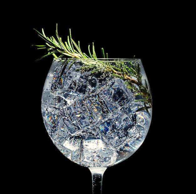 Alcoholic cocktail with ice. Soda and rosemary on a black space