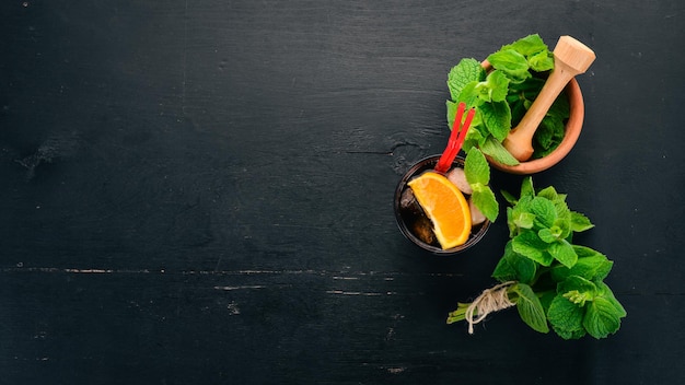 Alcoholic cocktail with orange and mint Negroni Long Island Rumcola On a black wooden background Free space for text