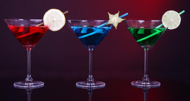 Alcoholic cocktails in martini glasses on dark red background