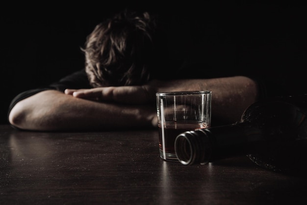 Alcoholic depressed and drunk addict man lies in front of whiskey glass Alcoholism concept