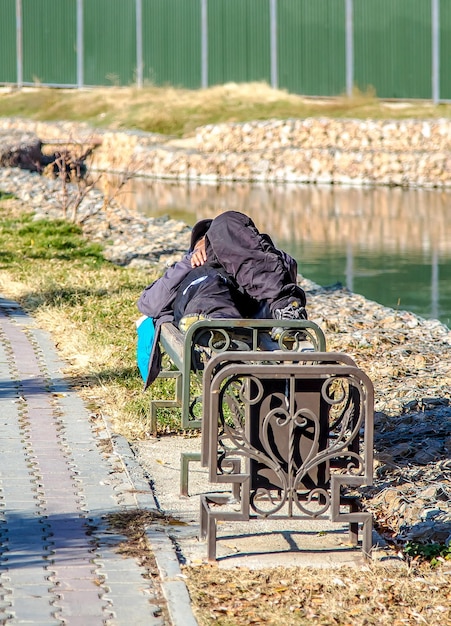 Alcoholic homeless man sleeping on a park bench