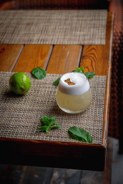 Alcoholic Peruvian cocktail Pisco Sour cocktail with ingredients with lemon on wooden background