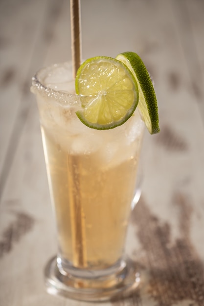 Alcoholic salty dog cocktail with grapefruit and lime in glass on wooden background, selective focus, vertical