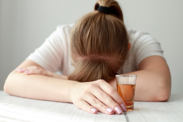 Alcoholic woman with a glass of cognac on the table