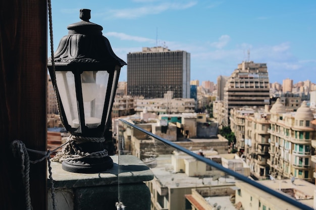 Alexandria, Egypt - 12.11.2021: Aerial view of old lantern lamp chandelier with rope and historical cityscape background