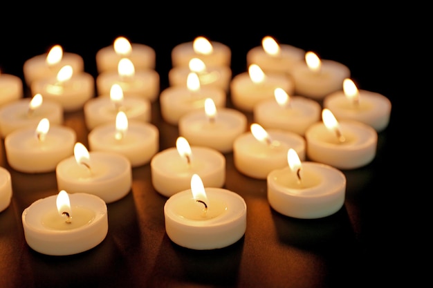 Alight candles in a row on black background