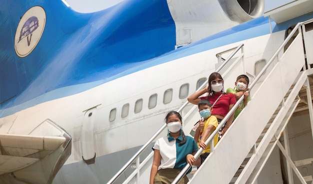 All the families were wearing masks to stand on the stairs for boarding the plane