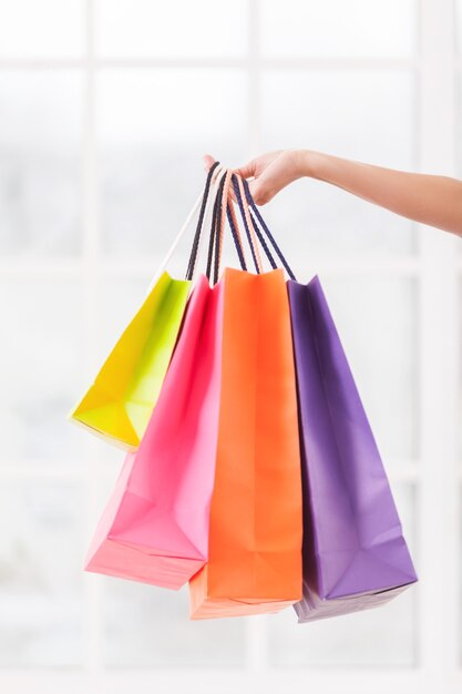 All I got on sale. Close-up of female hand holding multi colored shopping bags