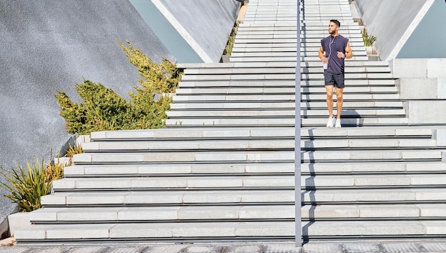 All I need is me and some motivation. Shot of a sporty young man listening to music and carrying a water bottle while exercising outdoors.