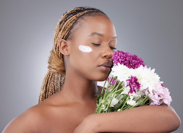 All the memories of everything youve ever smelled. Studio shot of an attractive young woman applying moisturiser while posing with flowers against a grey background.