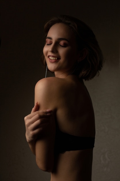 Alluring brunette model wears black lingerie posing at studio with shadows