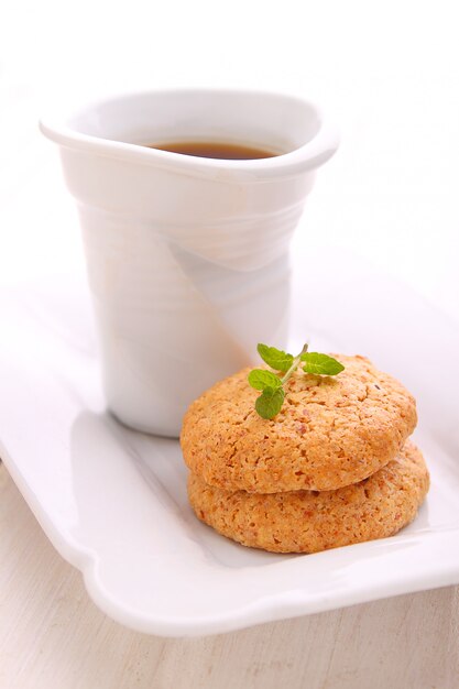 Almond cookies in a white plate with a cup of tea