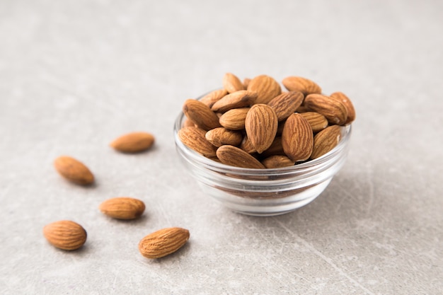 Photo almond in the glass bowl on stone table.