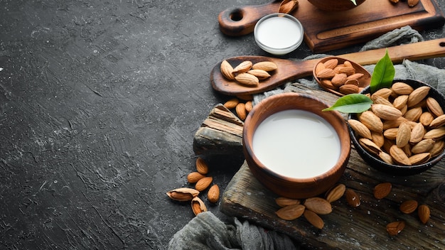 Almond milk and almonds on black stone background Top view Free space for your text