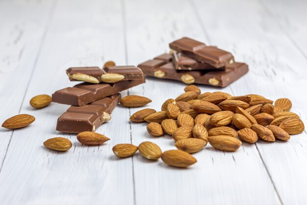 Photo almond and milk chocolate on the wooden table