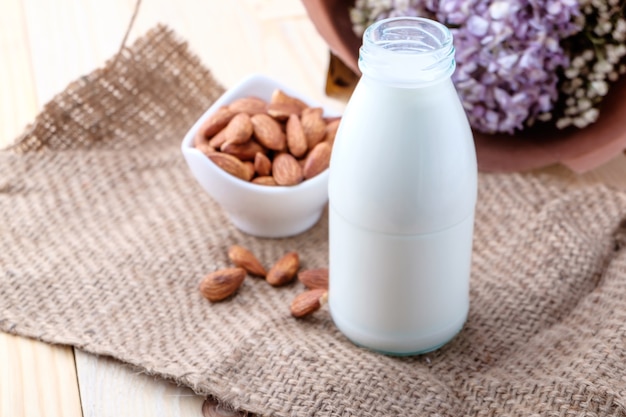 Almond milk in glass bottle on wood background