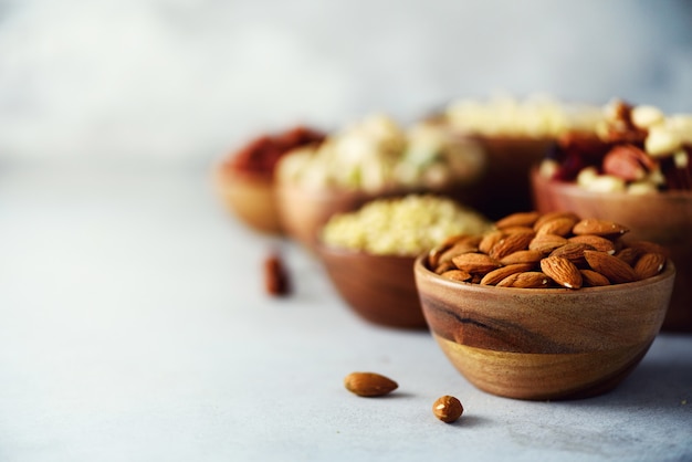 Almond nuts in wooden bowl. Assortment of nuts - cashew, hazelnuts, almonds, walnuts, pistachio, pecans, pine nuts, peanut, raisins