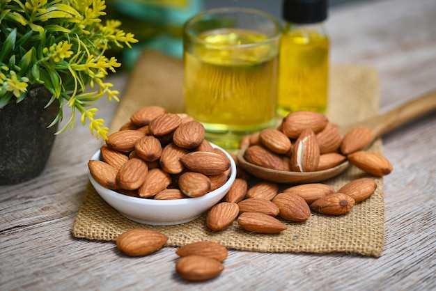 Almond oil and Almonds nuts on wooden Delicious sweet almonds oil in glass roasted almond nut for healthy food and snack organic vegetable oils for cooking or spa concept