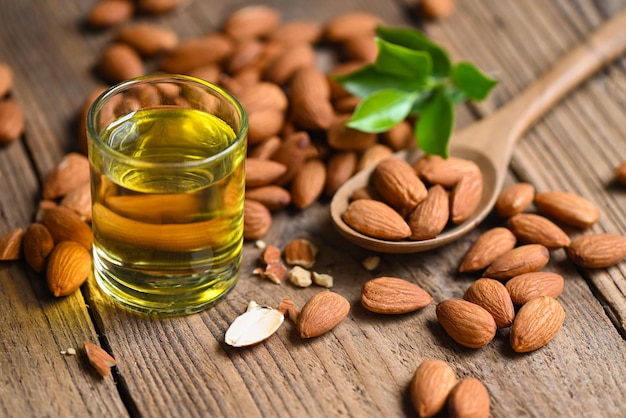 Almond oil and Almonds nuts on wooden, Delicious sweet almonds oil in glass, roasted almond nut for healthy food and snack organic vegetable oils for cooking or spa concept