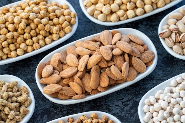 Almond in selective focus Nuts on plate on a dark background Walnut Chickpeas White Chickpeas Dry mulberry almond cashew pistachio Types of nuts on the plate