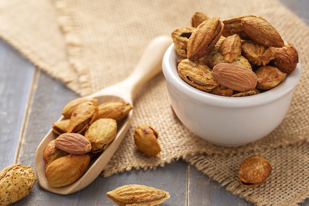 Almonds in a black bowl against dark rustic wooden background