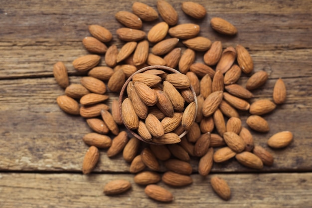 Almonds in brown bowl on wooden background